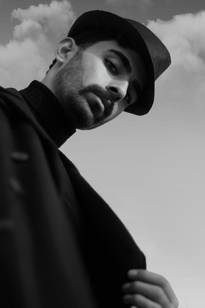 Sophisticated black and white portrait of a man in a hat, exuding elegance and mystery.